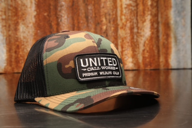 Green Camo/ Black Yupoong Trucker Hat with Black and White Stitched Patch